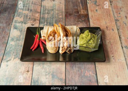 Mexican-style pulled pork wraps with shredded beef and guacamole paste with hot red peppers Stock Photo