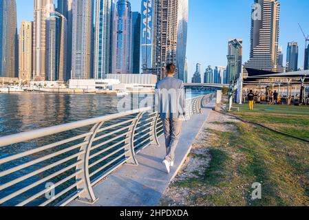 Young man walking at the promenade in Dubai Marina. Stock Photo