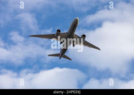 Airplane flying under clouds in the daytime Stock Photo