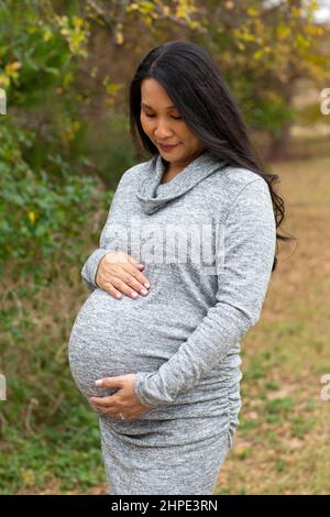 Happy Asian pregnant woman holding her stomach Stock Photo - Alamy