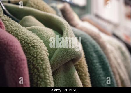 Elegant coats and jackets made of faux fur hang on rack Stock Photo