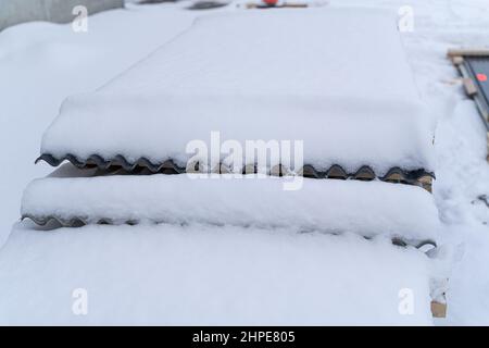 Pile of Corrugated roofing sheet stacked outside in snow Stock Photo