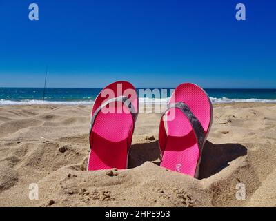 Pair of pink slippers in a sand Stock Photo