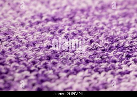 Full frame macro abstract texture background of hand-knitted yarn fabric in a basic garter stitch, in varying shades of purple and white Stock Photo