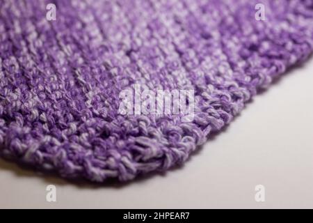 Full frame macro abstract texture background of hand-knitted yarn fabric in a basic garter stitch, in varying shades of purple and white Stock Photo