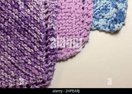 Full frame macro abstract texture background of hand-knitted yarn fabric in a basic garter stitch, in varying shades of purple and white Stock Photo