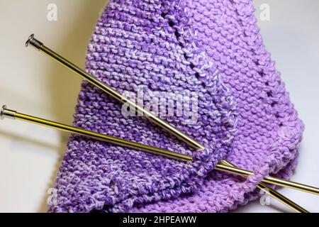 Full frame macro abstract texture background of hand-knitted yarn fabric in a basic garter stitch, in varying shades of purple and white Stock Photo