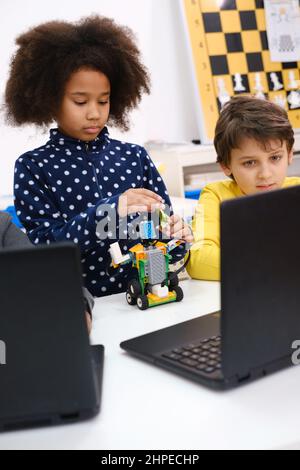 Kids learning coding, science and technology at school class. African American and Caucasian children studding with laptop computers on STEM lesson Stock Photo