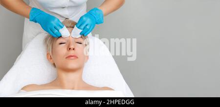 Professional cosmetologist does a deep mechanical cleaning forehead of the client's face. Top view. Acne treatment concept. Stock Photo