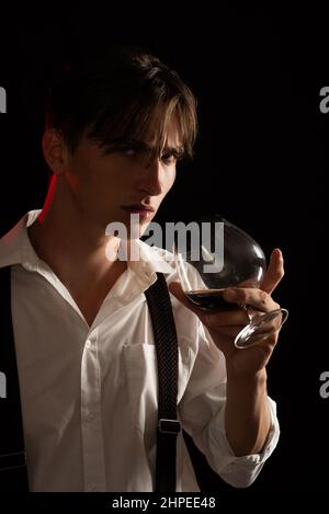 Man holds glass brandy. Young man drink cognac. Stylish rich man holding a glass of old whisky. Guy holding a glass of whisky. Stock Photo
