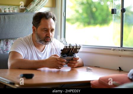 motorhome travel concept. Man controling a drone.a man controls a drone from the window of a motorhome Stock Photo