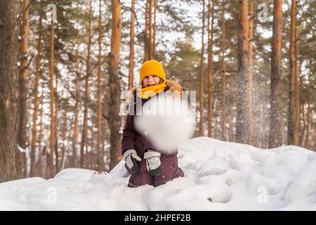 cute girl in winter jumpsuit playing in the snow, throws a snowball Stock Photo