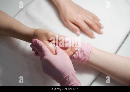 Close-up hands beautician, woman's hands receive manicure treatment, master makes a hand massage in a beauty salon. Spa nail and hand care concept Stock Photo