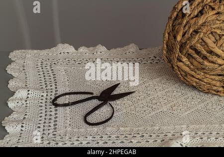 Old rusty scissors on white crochet table mat. Antique japanese bonsai scissors. Stock Photo