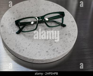 Dark green frame glasses isolated on white background. Reading glasses with dark frames on round white board. Stock Photo