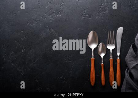 Vintage silverware. Rustic vintage set of wooden spoon and fork on black background. Top view. Mock up. Stock Photo