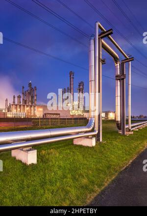 Construction with pipeline and Illuminated petrochemical production plant at twilight, Port of Antwerp. Stock Photo