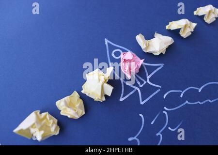 Lot of crumpled papers lying on blue paper with painted rocket Stock Photo