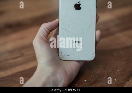 PARIS, FRANCE - JULY 03, 2020: Woman's hand holds broken background screen of iPhone 8 Stock Photo