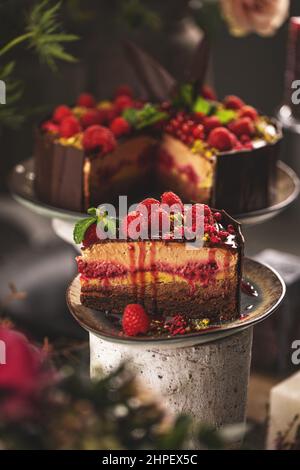 Slice of delicious layered mousse cake with melted chocolate topping decorated with raspberries Stock Photo