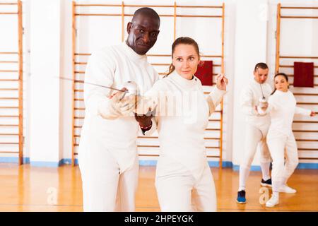 fencer practicing movements with african american trainer Stock Photo