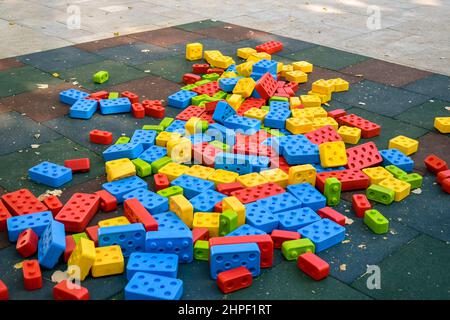 Large multi-colored plastic construction blocks are scattered around playground. Outdoor games for children. Close-up. Copy space. Selective focus. Stock Photo