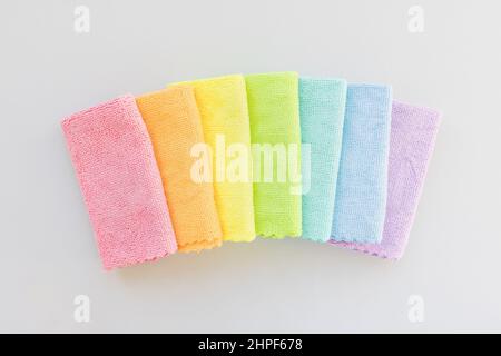 New folded microfiber cloth for cleaning in seven rainbow colors on gray background. Cleaning micro fabric towels for dusting and polishing. Domestic household cleaning service concept. Top view, copy space Stock Photo