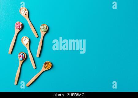 Top view Variety of vitamin and mineral pills in wooden spoon on Colored background. Top view of assorted pharmaceutical medicine pills. Dietary suppl Stock Photo