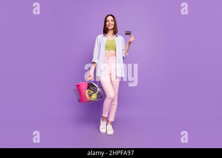 Full size photo of lovely brunette millennial lady online flea-market wear singlet shirt jeans footwear isolated on violet background Stock Photo