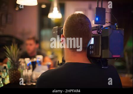 Behind the scenes. Cameraman shooting the film scene with his camera on outdoor set. Photography director in movie filmmaking action Stock Photo