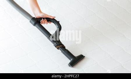 Vacuum cleaner machine in female hand do disinfection surfaces, cleanliness in hotel apartment. Woman do Professional cleaning mattress by vacuum Stock Photo