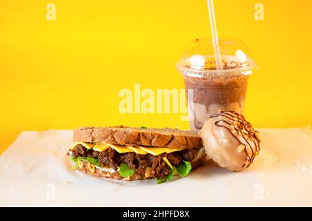 Rye bread pulled beef sandwich with donut and iced coffee drink Stock Photo