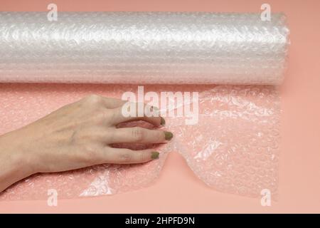 female hand crumples bubble wrap on a pink background. High quality photo Stock Photo
