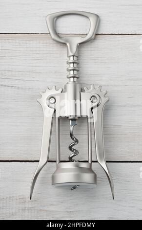 Front view of steel winged corkscrew bottle opener on white wooden background Stock Photo