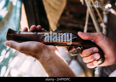 Old pistol with a wooden hilt in male hands. Medieval weapons Stock Photo