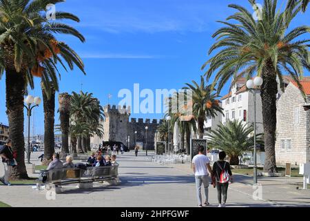 Trogir, Croatia - People walking along the Riva or Promenade toward Kamerlengo Fortress in the old town on a sunny day Stock Photo