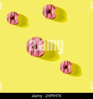 pattern made of Freshly baked donuts  with icing and sprinkles for breakfast on a yellow background . Sweet background. Bakery, baking concept. Stock Photo