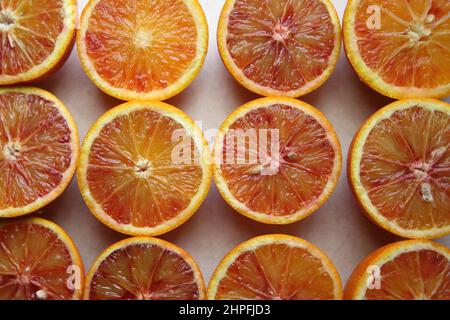 Freshly sliced Blood Oranges (Citrus × sinensis 'Blood Orange') arranged in a pattern on a light surface. Stock Photo