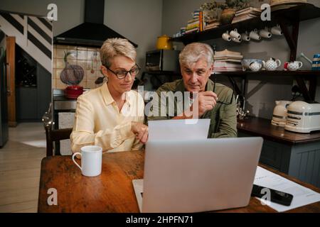Caucasian senior couple working on the financials in the kitchen Stock Photo