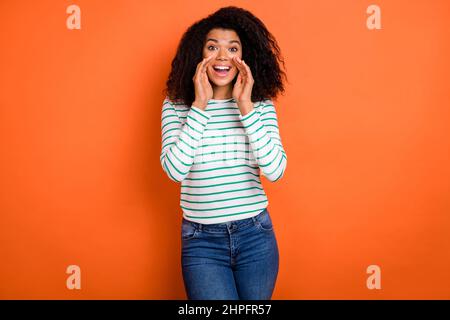 Photo of sweet millennial curly hairdo lady tell secret wear white shirt isolated on orange color background Stock Photo