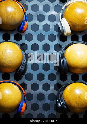 Wooden balls in headphones hang in two rows on wall with a honeycomb pattern. There is empty space for text in the center of the photo. Stock Photo