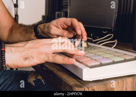Caucasian hands using a midi controller in a home studio making urban music beat, music industry and production concept. Stock Photo