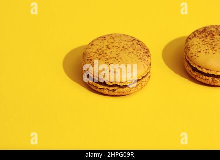 Two Yellow french macaroons on bright yellow background.  Delicious meringue cookies. Food concept Stock Photo