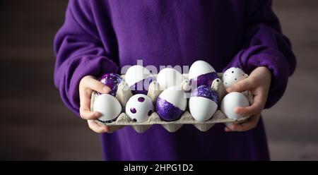 Close-up of a tray of purple Easter eggs in the hands of a child. Stock Photo
