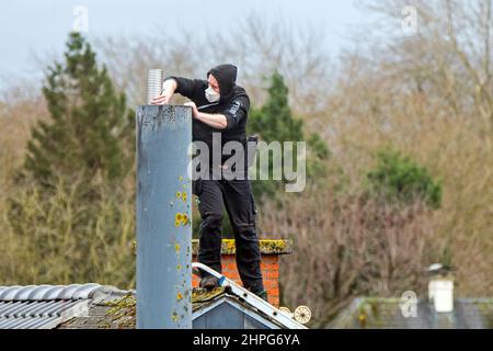 Roofer / chimney contractor working on roof for repair work on a stormy day after passage of storms Eunice and Franklin in February 2022 Stock Photo