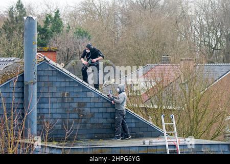 Roofers / roofing contractors working on roof for repair work on a stormy day after passage of storms Eunice and Franklin in February 2022 Stock Photo