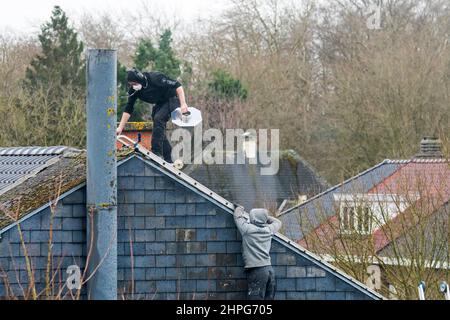 Roofers / roofing contractors working on roof for repair work on a stormy day after passage of storms Eunice and Franklin in February 2022 Stock Photo