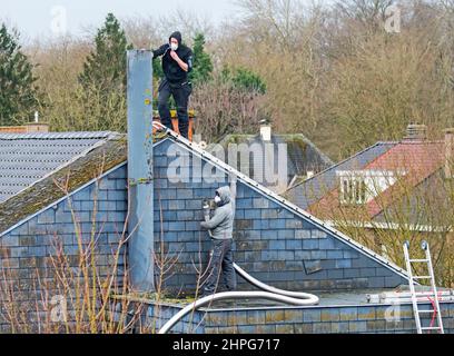 Roofer / chimney contractor working on roof for repair work on a stormy day after passage of storms Eunice and Franklin in February 2022 Stock Photo