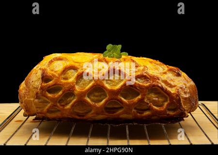 Wellington steak wrapped in medium rare beef and finely decorated gold puff pastry with a mint leaf placed on the grill for christmas festivity Stock Photo