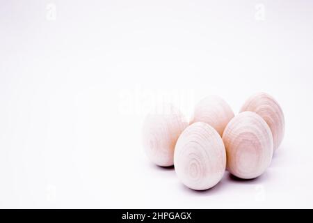 Five hand-made unpainted wooden eggs on a white background. Copy space. Stock Photo